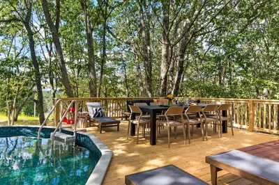 a deck with a table and chairs next to a swimming pool at Retreat HotTub FirePit Sauna GameRm Pool Playroom in East Stroudsburg