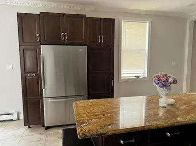 a kitchen with a refrigerator and a vase of flowers on a counter at Americana in Jersey City