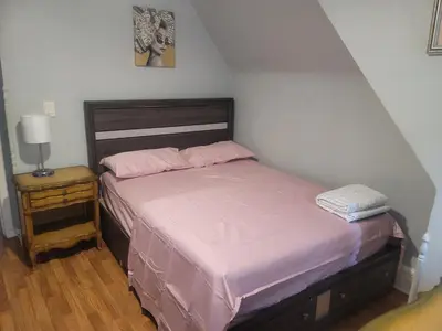 a bedroom with a bed with pink sheets and a night stand at Grove#1 in Irvington