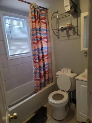 a bathroom with a toilet and a shower curtain at Grove#1 in Irvington