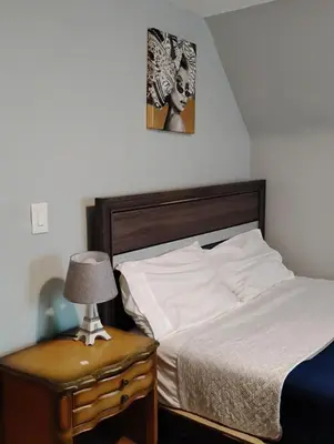 a bedroom with a bed and a table with a lamp at Grove#1 in Irvington