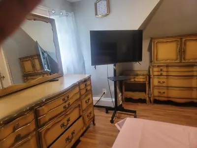 a bedroom with a dresser with a mirror and a television at Grove#1 in Irvington