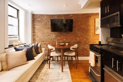 a living room with a couch and a brick wall at Urban Oasis 1BR East Village Hideaway with Patio! in New York