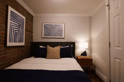 a bedroom with a bed and a brick wall at Urban Oasis 1BR East Village Hideaway with Patio! in New York