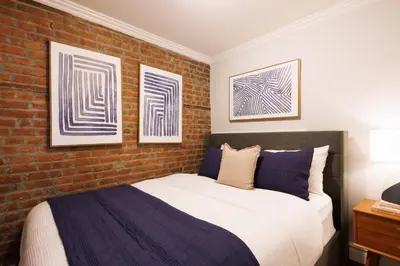 a bedroom with a bed and a brick wall at Urban Oasis 1BR East Village Hideaway with Patio! in New York
