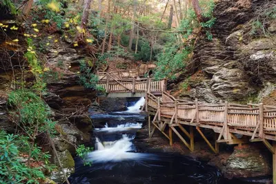 a wooden bridge over a river with a waterfall at 5 min Shawnee Mountain, Hot tub, Game Rm, 3 Kings in East Stroudsburg