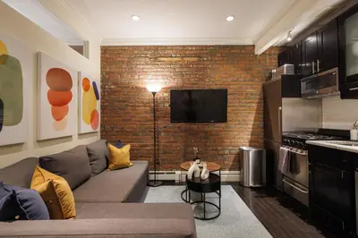 a living room with a couch and a brick wall at Refined & Stylish Manhattan Haven in New York