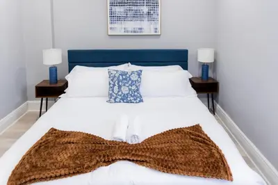 a bedroom with a white bed with a brown scarf on it at Spacious 3 bedrooms Apartment-20 mins to NYC in West New York