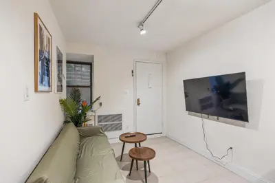 a living room with a couch and a tv on a wall at The NYC Edition Times Square in New York