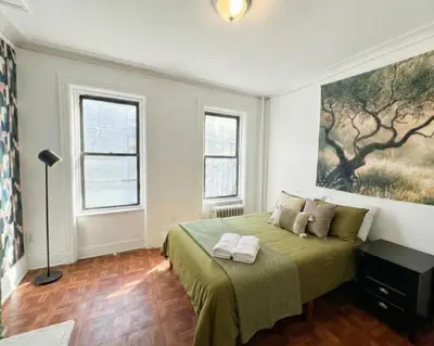 a bedroom with a bed and a painting on the wall at Upper West Side Apartment 10 minutes walk From Central Park in New York