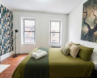 a bedroom with a green bed with two towels on it at Upper West Side Apartment 10 minutes walk From Central Park in New York