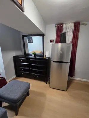 a living room with a refrigerator and a dresser at Newly renovated 1 room in a 3-bedroom apartment with private toilet ands bathroom in Irvington