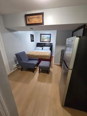 a small bedroom with a bed and a refrigerator at Newly renovated 1 room in a 3-bedroom apartment with private toilet ands bathroom in Irvington