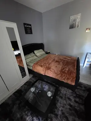 a bedroom with a bed with a mirror and a table at Newly Built detached studio apartment with private toilet and bath in Irvington