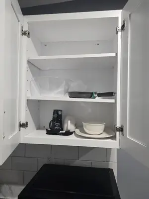 a white cabinet with a plate and dishes in it at Newly Built detached studio apartment with private toilet and bath in Irvington