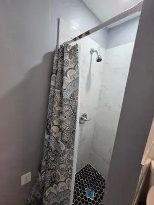 a bathroom with a shower with a tile floor at Renovated Room with Private Bath in Ground Floor 3BR in Irvington