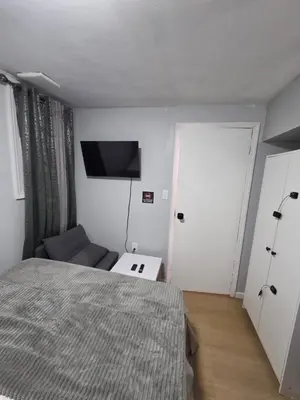 a bedroom with a bed and a tv on the wall at A newly renovated room with private toilet & bathroom in a 3 bedroom apartment on the ground floor in Irvington