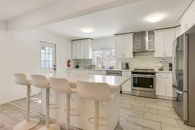 a kitchen with white cabinets and a kitchen island with stools at Game Room and Hot Tub Family Gem on Lake Hopatcong