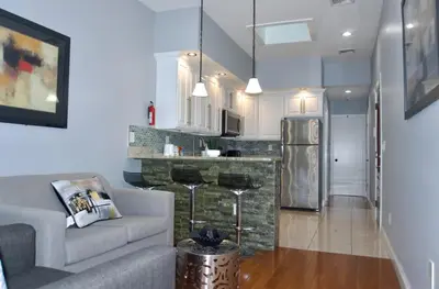 a living room with a couch and a kitchen at New York private room 29 in West New York