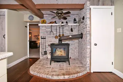 a brick fireplace with a stove in a living room at Creekside Farmstead - Pool - Hot Tub - 3 Min to Lake - Pets Allowed in Auburn