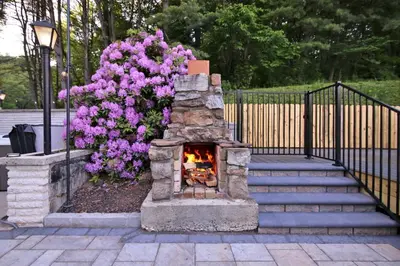 a fireplace in a yard next to some flowers at Creekside Farmstead - Pool - Hot Tub - 3 Min to Lake - Pets Allowed in Auburn