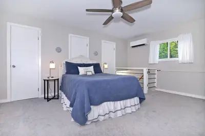 a bedroom with a blue bed and a ceiling fan at Creekside Farmstead - Pool - Hot Tub - 3 Min to Lake - Pets Allowed in Auburn