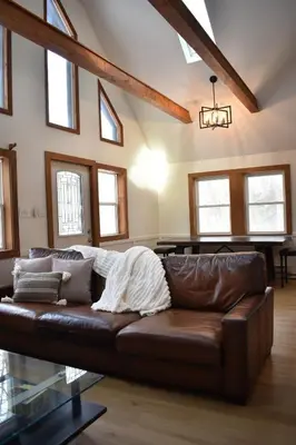 a brown leather couch in a living room with windows at A-Frame Chalet Ski Lodge Near Shawnee in East Stroudsburg
