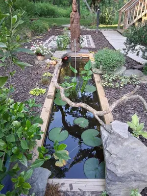 a garden with a pond with a statue and water lilies at Black Top Retreat in Wyalusing