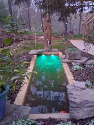 a koi pond with a statue in a garden at Black Top Retreat in Wyalusing