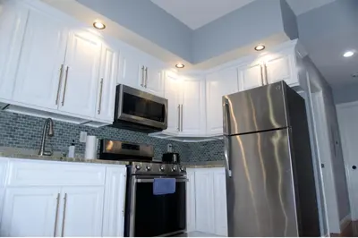 a kitchen with white cabinets and a stainless steel refrigerator at New York Private room 30 in West New York