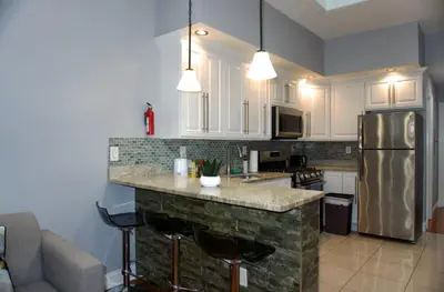 a kitchen with white cabinets and a stone counter top at New York Private room 30 in West New York