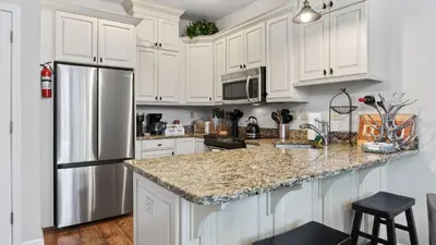 a kitchen with white cabinets and a stainless steel refrigerator at Crestline Retreat by AvantStay Luxury Mountain Condo with Hot Tub BBQ Game Room Steps to Big Boulder in Lake Harmony