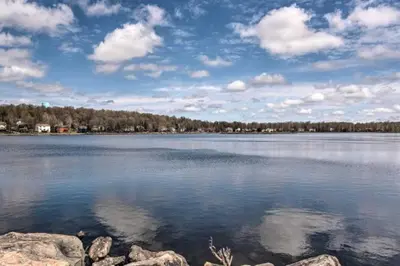 a large body of water with rocks in the foreground at Luxury Pocono Escape ~ Sauna | Hot Tub | Mini Golf in Tobyhanna