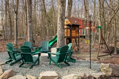 a playground with green chairs and a tree house at Luxury Pocono Escape ~ Sauna | Hot Tub | Mini Golf in Tobyhanna
