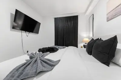 a bedroom with a white bed with a television on the wall at Modern 3 Bedroom 7 minutes to Manhattan in Jersey City