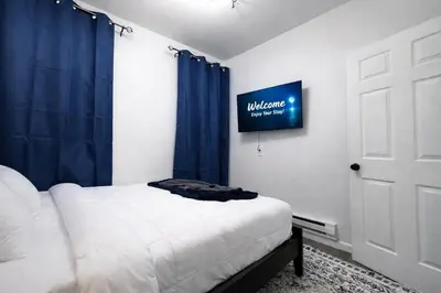 a bedroom with a bed and a blue curtain at JC Central Stylish Stay Near Manhattan 1A in Jersey City