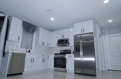 a kitchen with white cabinets and stainless steel appliances at Big apple room 35 in West New York