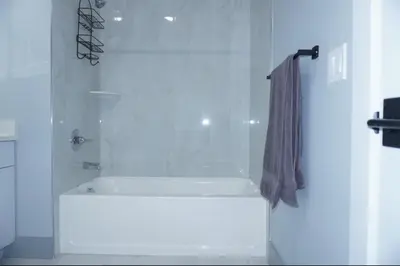 a white bathroom with a shower with a shower curtain at Big apple room 35 in West New York