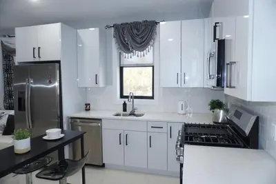 a kitchen with white cabinets and a sink and a refrigerator at Big apple room 35 in West New York