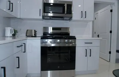 a white kitchen with a stove and a microwave at Big apple room 35 in West New York