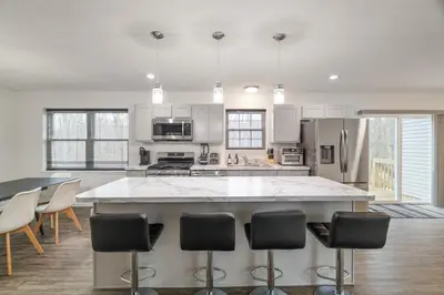 a kitchen with a large island with bar chairs at The Aerie House In Tobyhanna in Tobyhanna