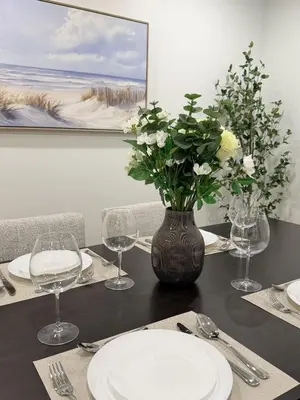 a table with a vase of flowers and plates on it at 35 to NYC - Netflix - 2Beds -1BR - FIFA 2026 in Passaic