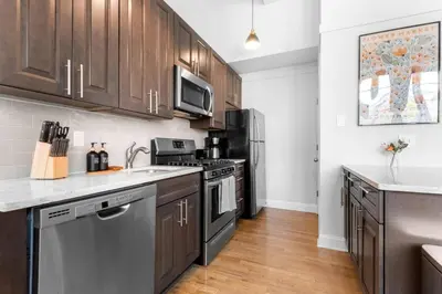 a kitchen with stainless steel appliances and wooden cabinets at 2BR City Getaway - Close to NYC - Prime Location in Hoboken