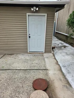 a garage with a white door and a driveway at Newly Renovated Detached Studio apartment in Irvington