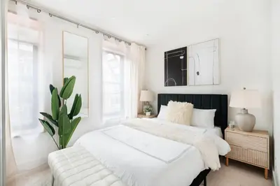 a white bedroom with a large bed and a plant at 48-4FE 2BR Prime Midtown West in New York