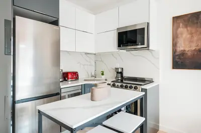 a kitchen with white cabinets and a stainless steel refrigerator at 319-3A XL New Modern 1BR Union Square WD in Unit in New York