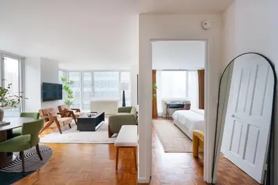 a room with a bed and a living room with a mirror at 43-20A Newly furnished 1BR- full service Doorman laundry Gym Business Center in New York