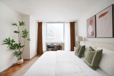 a white bedroom with a large white bed with green pillows at 43-20A Newly furnished 1BR- full service Doorman laundry Gym Business Center in New York