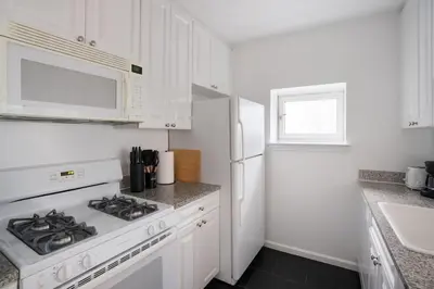 a white kitchen with a stove and a microwave at 43-20A Newly furnished 1BR- full service Doorman laundry Gym Business Center in New York