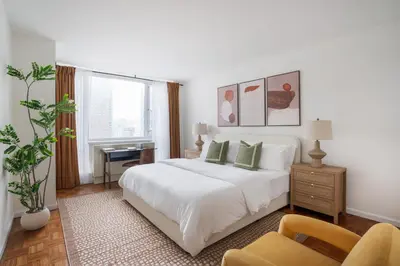 a white bedroom with a bed and a chair at 43-20A Newly furnished 1BR- full service Doorman laundry Gym Business Center in New York